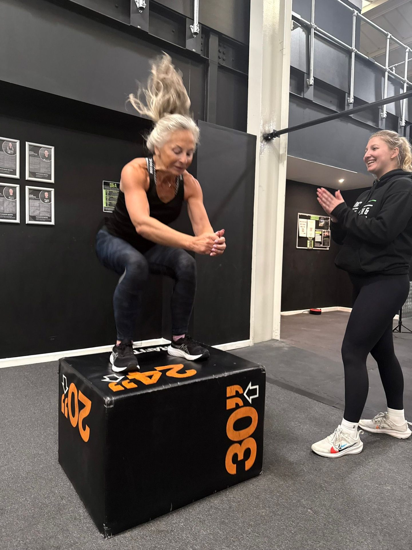 Personal training client performing a box jump with coach support at JWC